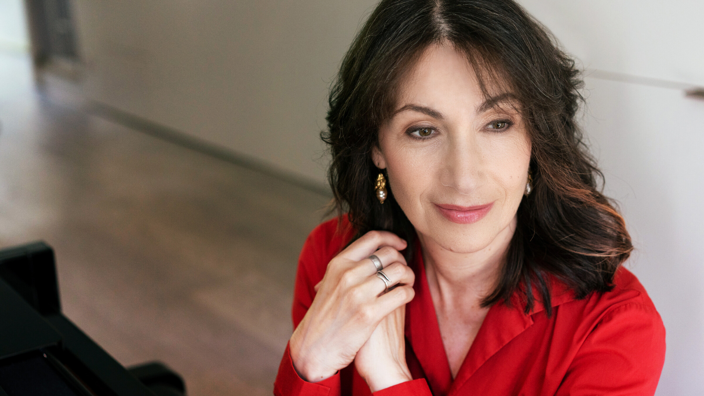 Eleonor Bindman headshot at piano in red shirt - closeup