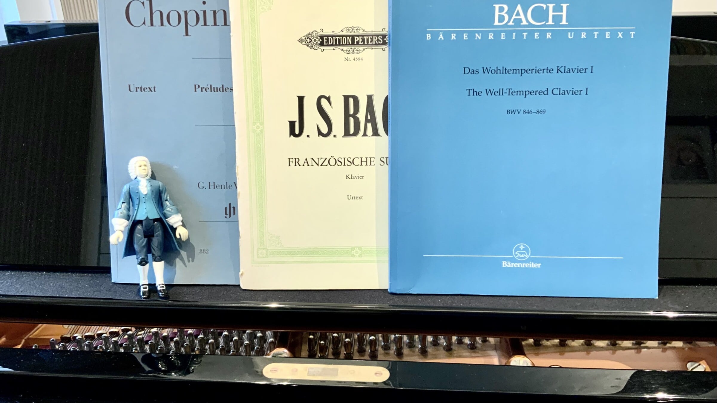 Bach action figure in front of scores on a piano