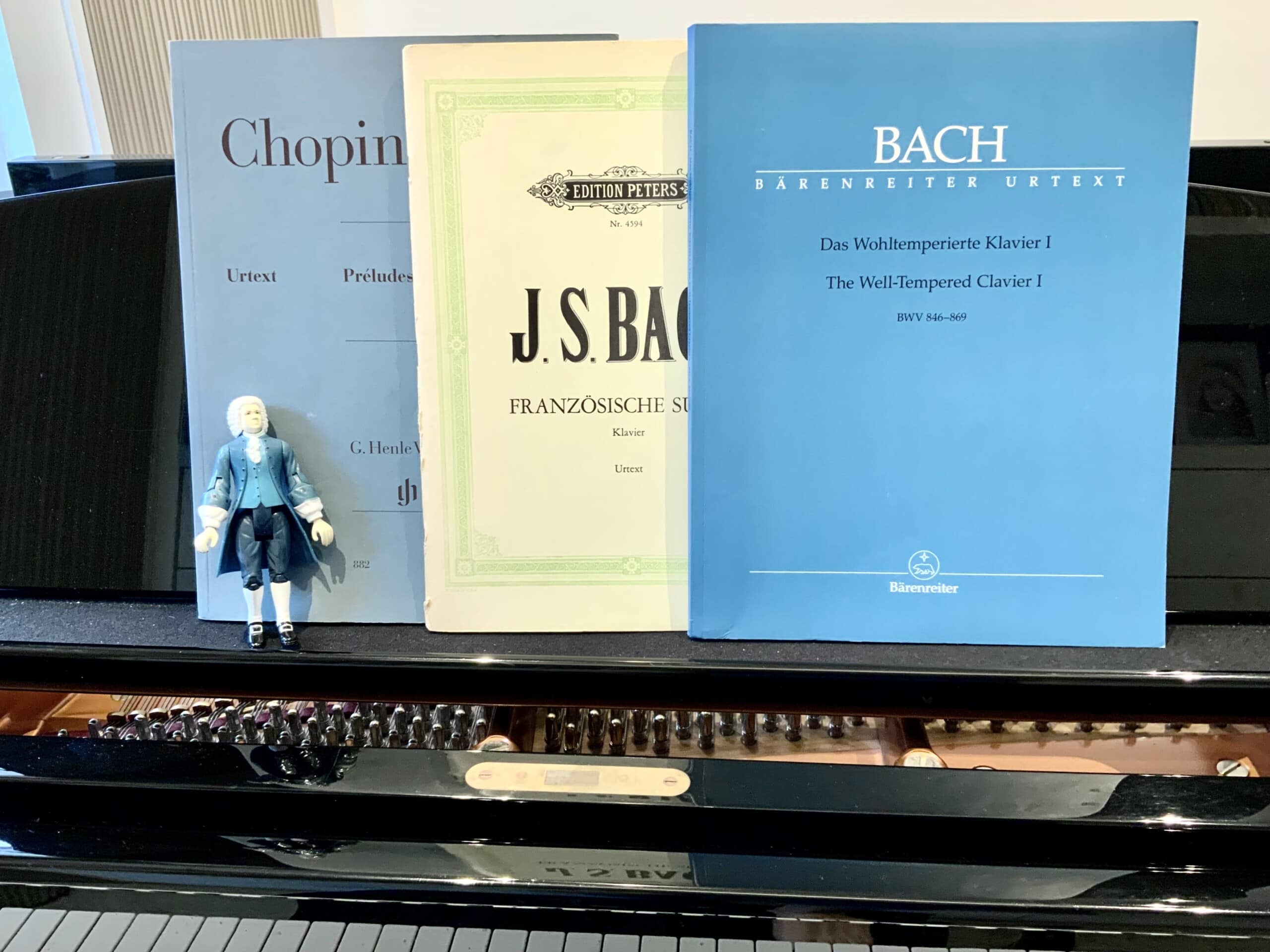 Bach action figure in front of scores on a piano
