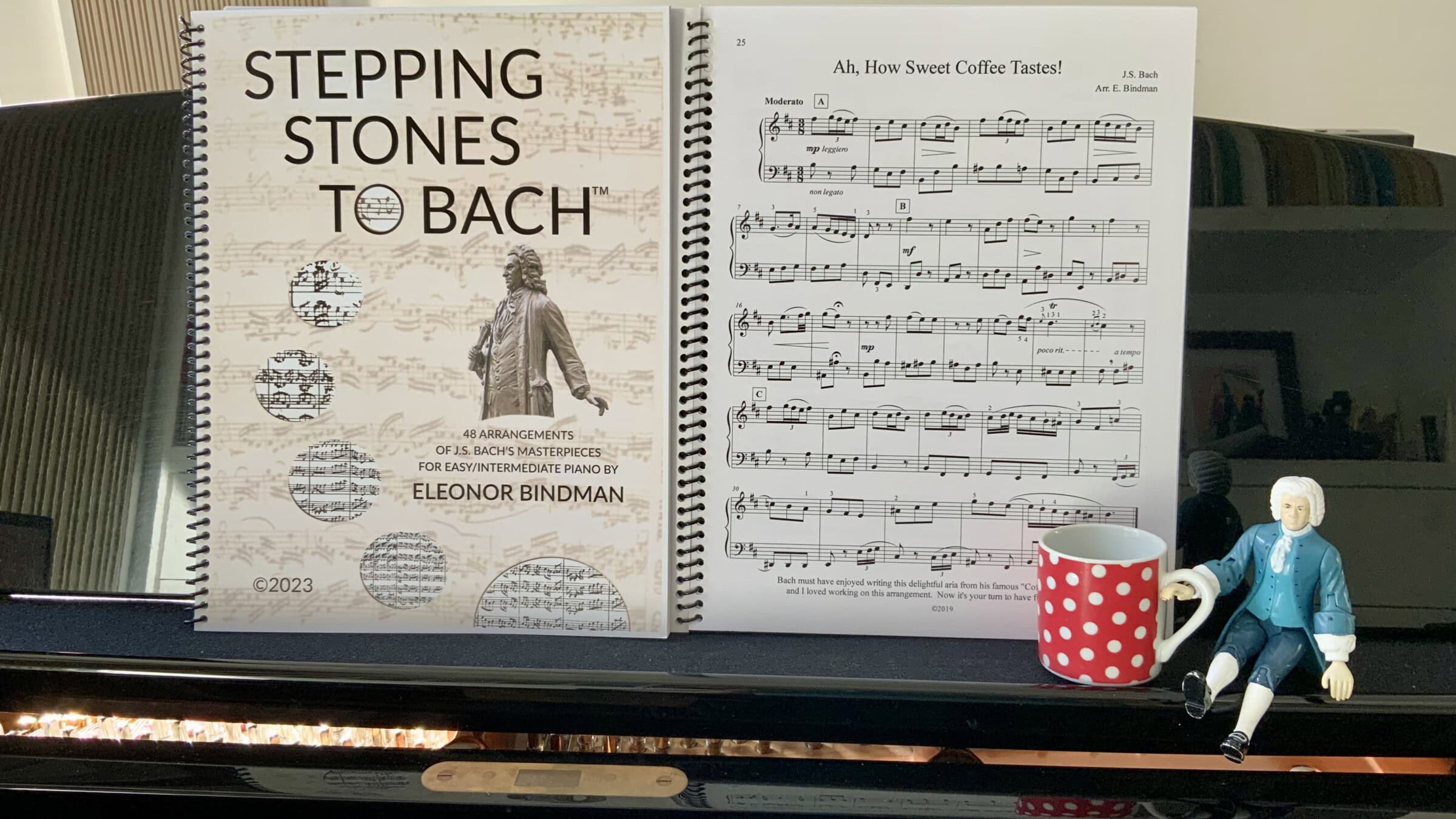 Bach statue on piano with coffe and stepping stones to bach volume with the score of Ah How Sweet Coffee Tastes